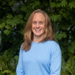 Smiling woman with red hair wearing a black shirt.