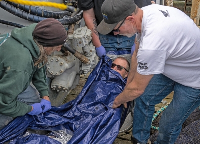 Commercial fishermen practice how to wrap a hypothermic patient and transport them to safety during a simulated first-aid training scenario aboard the fishing vessel Capt Ryan in Warrenton in 2023.  Credit: Chris Peterson, Action Works Photography