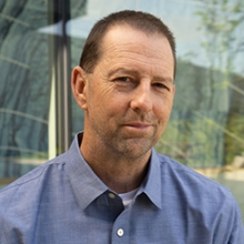 Dr. James Sulikowski. Photo Credit Adriene Koett-Cronn. Man wearing blue shirt with close cropped dark hair stands in front of window.